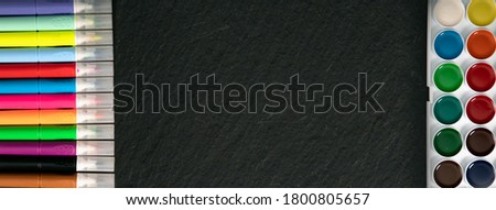 Colored markers and paints on black textural background. Suitable for advertising background. Suitable for mockups. Back to school, education concept.