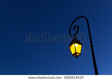 Yellow  light of night street city spiral metal shape lamppost on blue sky background  