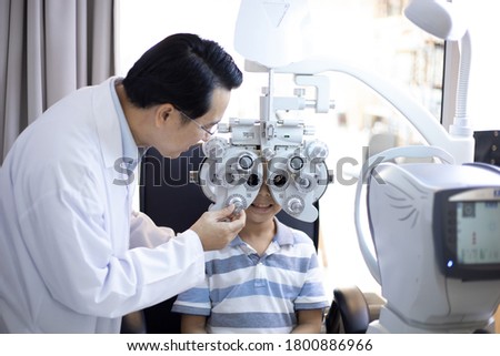 Asian optometrists are examining pediatric patients' eyes with the Autorefractor in a clinic.
