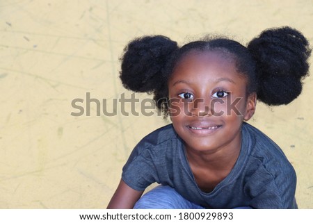 Cute young girl sitting on yellow background outdoors