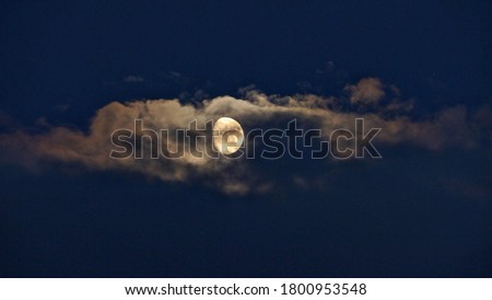 A picture of the moon behind clouds