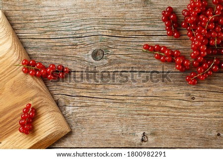 Fresh ripe red currants on rustic weathered wooden board