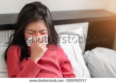 Sick asian girl have hight fever flu and sneezing into tissue on bed in bedroom, Healthcare and prevent the spread infection virus concept, Selective focus. Royalty-Free Stock Photo #1800983917