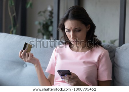Confused ethnic young woman disappointed with failure making payment online with credit card on cellphone gadget, unhappy indian Arabic female have problems with account security, shopping on web Royalty-Free Stock Photo #1800995452