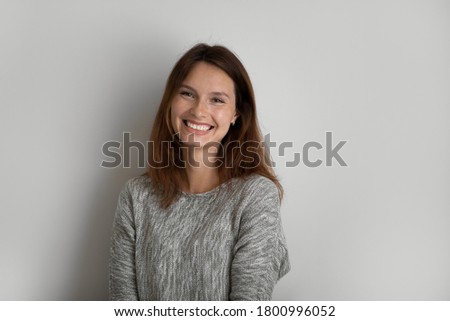 Profile picture of smiling young red-haired woman stand isolated on grey studio background show positive optimistic spirit, portrait of happy Caucasian female pose demonstrate white healthy teeth