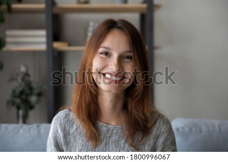 Profile picture of happy red-haired young Caucasian woman look at camera talk on video call at home, headshot portrait of smiling female have webcam virtual conference conversation, use new technology