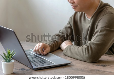 Young businessman sitting down and using his laptop to take a video call while working from home