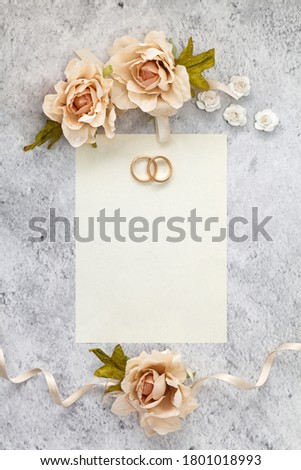 Wedding invitation card  paper laying on table decorated with roses.
