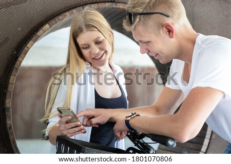 Happy young couple using smart phone application outdoors in urban environment.