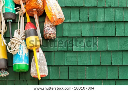 Lobster buoys hanging on a green wood shingled wall. Copy space.