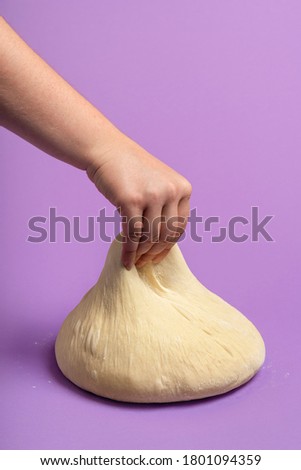 Woman kneading dough, isolated on a  purple seamless background. Testing the dough. Baking bread. Home cooking. Preparing pizza dough.