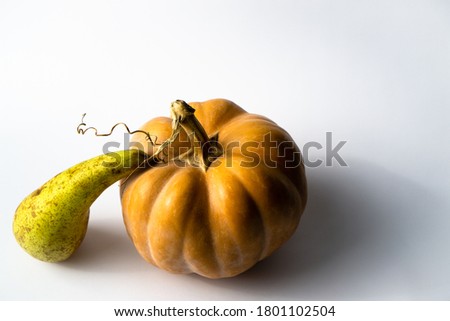Pear and pumpkin in still life on light surface with soft shadows. Autumn composition of fruits and vegetables for vegetarian menu.