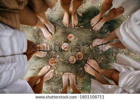 Female barefoot feet on dry grass standing in a circle with glasses of wine in the middle. Royalty-Free Stock Photo #1801108711