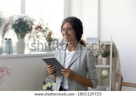 Happy young dreamy woman holding computer tablet in hands, looking away, thinking of future challenges, planning meeting with clients or personal brand development online, inspiration concept.