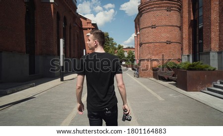 Young man takes pictures of beautiful buildings. Action. Guy takes photos on professional camera while walking around city. Attractive man takes professional pictures of urban architecture