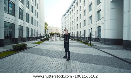 Photographer takes pictures of city's modern architecture. Action. Young man shoots modern architecture with professional camera. Photography is hobby