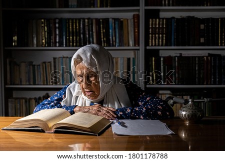 Old lady writing and reading some book at the morning light