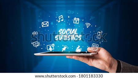 Young business person working on tablet and shows the inscription: SOCIAL STATISTICS