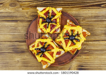 Funny sandwiches with spider and spider web for Halloween party on wooden table. Top view