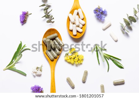 Capsules of natural collagen and herbal detox capsules for beauty and immunity support on white background with flowers and herbs top view. Healthy lifestyle concept. Royalty-Free Stock Photo #1801201057