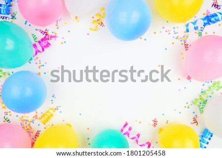 Birthday party theme frame on a white background. Top down view with balloons, confetti and streamers. Copy space.