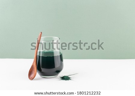 spirulina drink in a glass on a white table, green background, minimalism Royalty-Free Stock Photo #1801212232