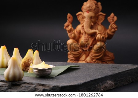 Modak- a traditional dish made on Ganpati festival in India. served with clarified butter. Ganesh idol at background