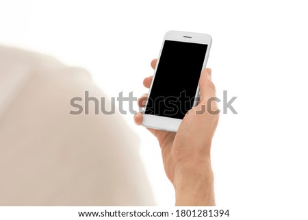 Man holding a smartphone with empty black screen. Mobile phone in a vertical position in hands and isolated on white background. Studio shot. Third person view. Camera shot from over shoulder.