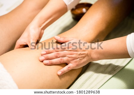 Masseuse woman hands giving a leg massage, finding a contracture, trigger point, a tight part in the muscle Royalty-Free Stock Photo #1801289638