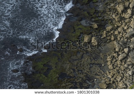 This picture the aerial view of waves splashing the coastal rocks 
