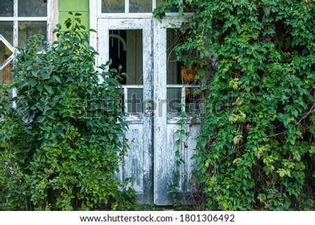 Facade of abandoned house. Old wooden door. Old wall with big vintage gates
