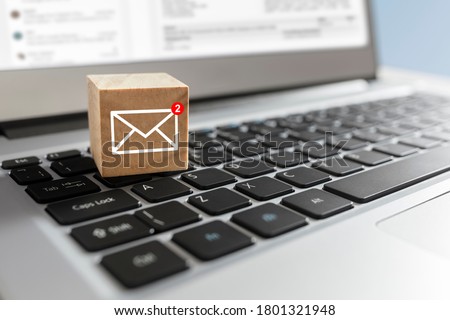 Email symbol on wooden block showing new message on laptop keyboard Royalty-Free Stock Photo #1801321948