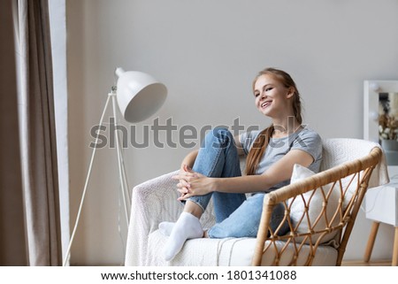 Young millennial redhead woman sitting on modern chair enjoying morning at home. Good weekend.