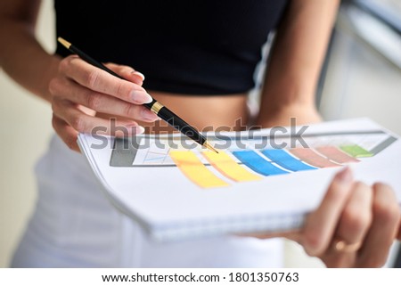 Close-up picture of paper sheet with colorful chart, held in hands of young businesswoman, Office worker getting ready for presentation.
