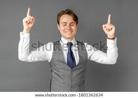 Emotional portrait of a businessman who shows his hands up. Gray background. Business and finance concept
