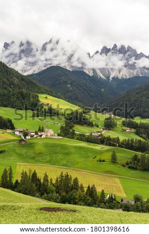 Lush green meadows and an isolated church in the Italian Dolomites