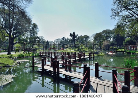 Photography of a pathway bridge across a lake in a park at Buenos Aires