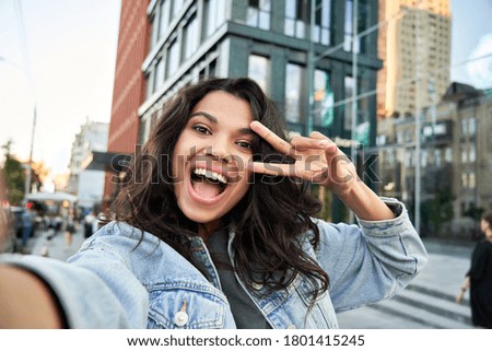 Happy African American hipster girl blogger influencer recording vlog holding looking at camera. Black teen travel vlogger influencer shooting video, streaming on urban city street, headshot.