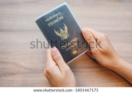 Someone hands holding a Thailand passport in book cover before take a flight. A passport is an easily recognized travel document that identifies you and authorizes you to travel.
