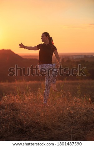 The girl does exercises in nature during sunset. The pictures are taken against the sun