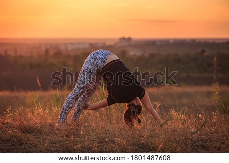 The girl does exercises in nature during sunset. The pictures are taken against the sun