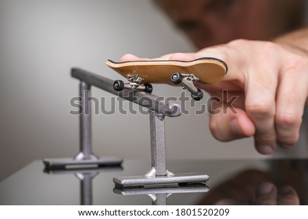 Man rolls a fingerboard on a gray metal railing