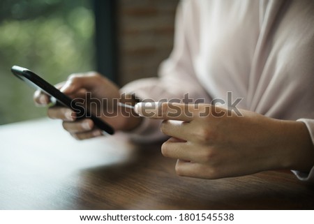 Close up of a teenage woman holding credit card and smart phone make online payment. Business and finacne stock photo.