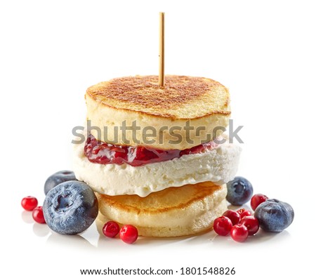 dessert of pancakes and ice cream decorated with jam and fresh berries isolated on white background
