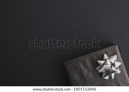 Gift box with silver bow on dark background. Black friday sale, christmas or birthday party concept. Top view, flat lay, copy space