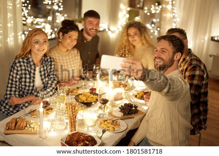 holidays, celebration and people concept - happy friends taking selfie with smartphone at home christmas dinner party