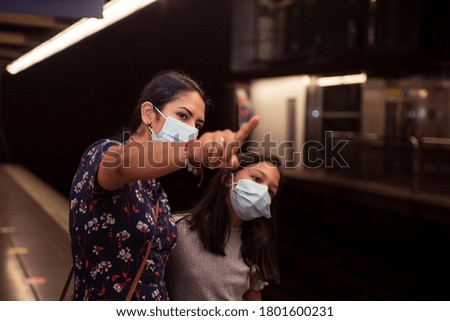Latin woman pointing her finger and teaching her daughter in the subway station.