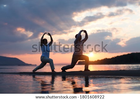 Man and woman doing Tai Chi chuan at sunset on the beach.  solo outdoor activities. Social Distancing. Healthy lifestyle  concept.  Royalty-Free Stock Photo #1801608922