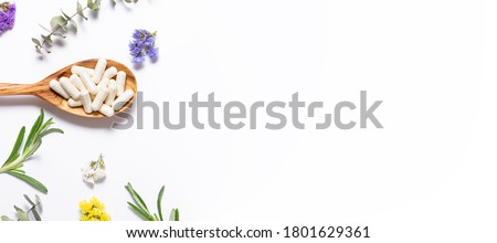 Collagen capsules for skin care and beauty in the wooden spoon on white background with herbs and flowers. Health care concept. Long banner format. Royalty-Free Stock Photo #1801629361
