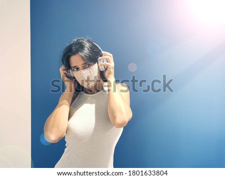 
Happy woman with mask listening to music on her headphones